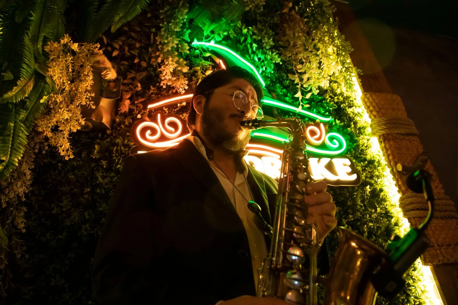 Saxofonista tocando en vivo en Mandrake, entre luces de neón